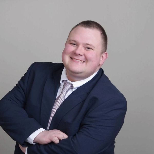 Smiling man in a suit with arms crossed.