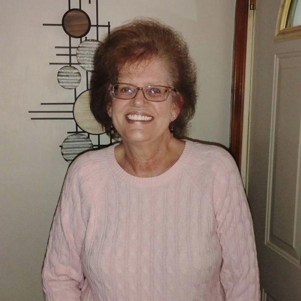 Smiling woman in pink sweater and glasses.
