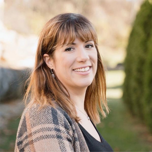 Smiling woman outdoors with a plaid jacket.