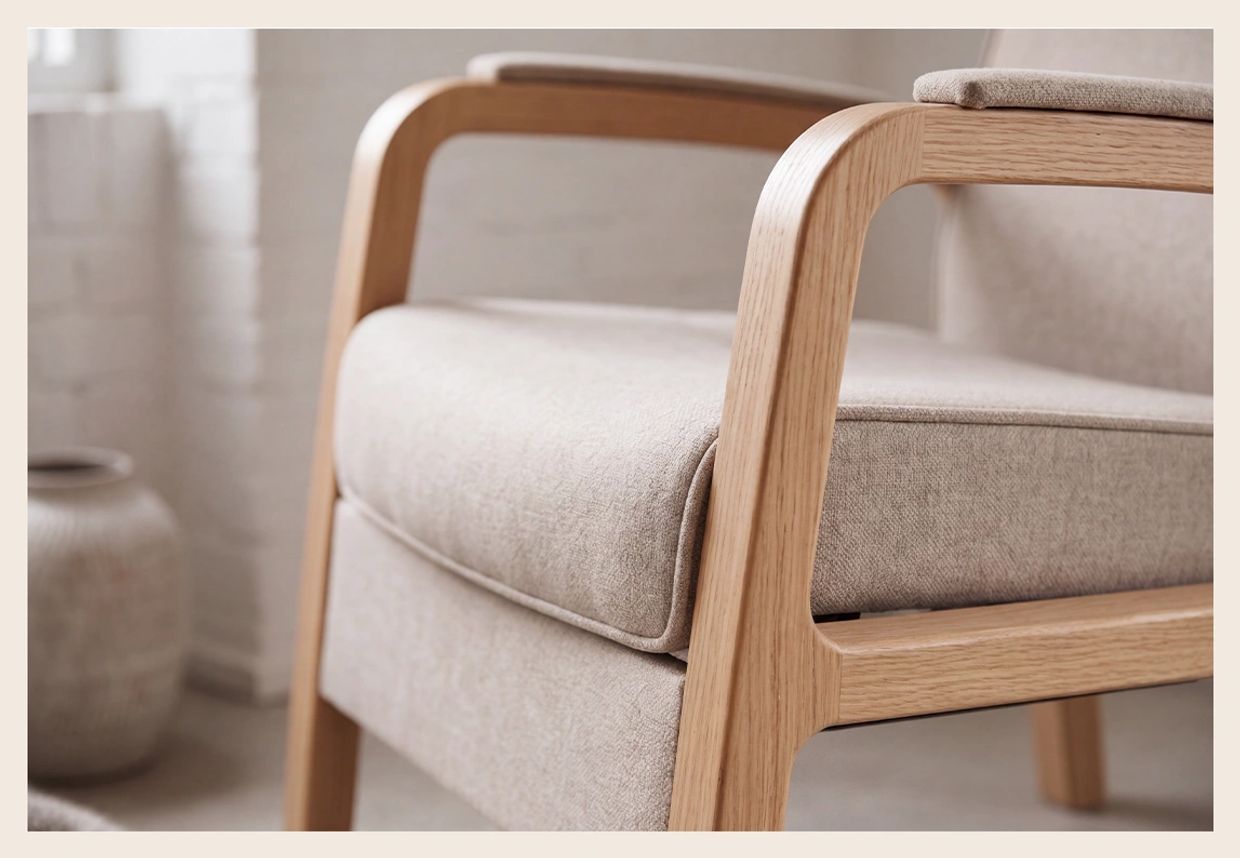 Close-up of a beige cushioned chair with wooden armrest.