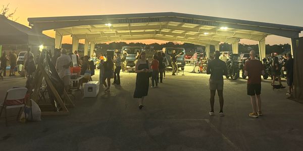 People gather under a pavilion at dusk for an event.