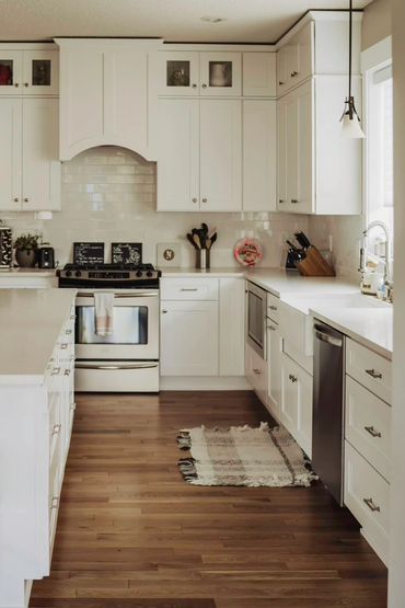Bright modern kitchen with white cabinetry and wood flooring.