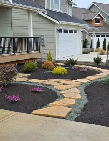 Modern front yard with stone pathways and colorful shrubs.