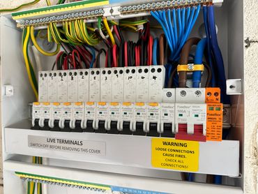 Electrical circuit breaker panel with labeled switches and warning signs.