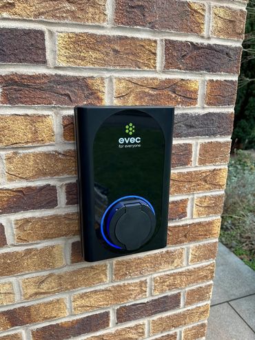 EVEC electric vehicle charging station mounted on a brick wall.