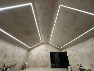 Room with modern recessed ceiling lights and unfinished walls.