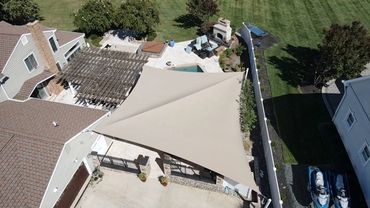 Aerial view of a backyard with a large beige shade sail.