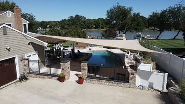 Backyard pool with a large shade sail and lake view.