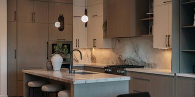 Modern kitchen with marble countertops and wood cabinetry.