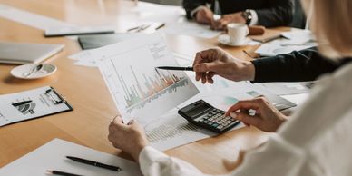 Person analyzing financial charts with calculator in a business meeting.