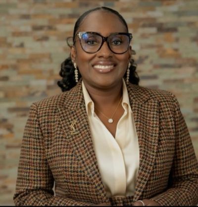 Professional woman smiling wearing glasses and a checked blazer.