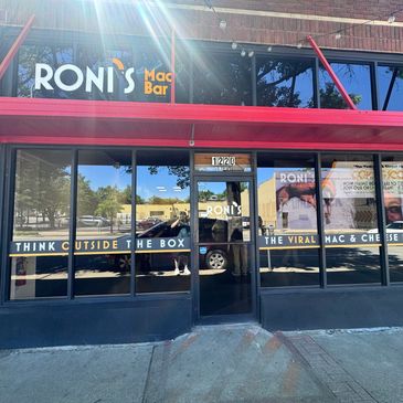 Exterior of Roni's Mac Bar with red awning and bold signage.