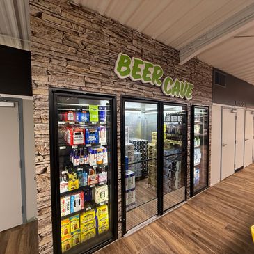 Entrance to a stone-themed beer cave cooler stocked with various beer brands.