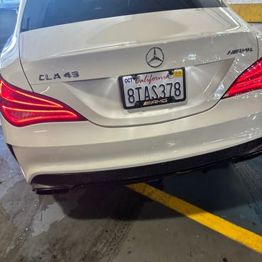 Rear view of a white Mercedes CLA 45 AMG with California license plate.