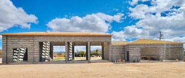 Partially constructed building with wooden roof framework under a blue sky.