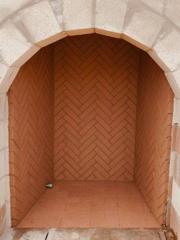 Empty brick alcove with an arched entrance and a small bottle inside.