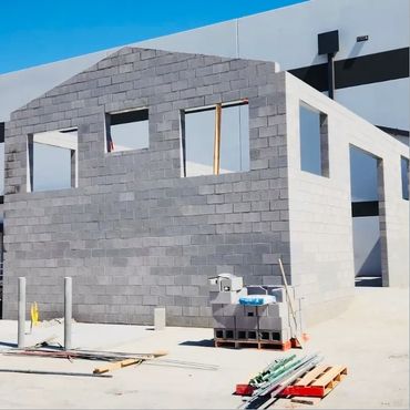 Unfinished building made of gray concrete blocks under clear blue sky.