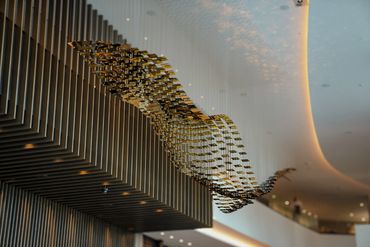 Modern ceiling installation with a wave of reflective gold squares.