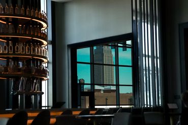 Bar interior with a window view of a tall building outside.