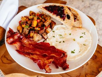 Breakfast plate with bacon, eggs, toast, and potatoes.