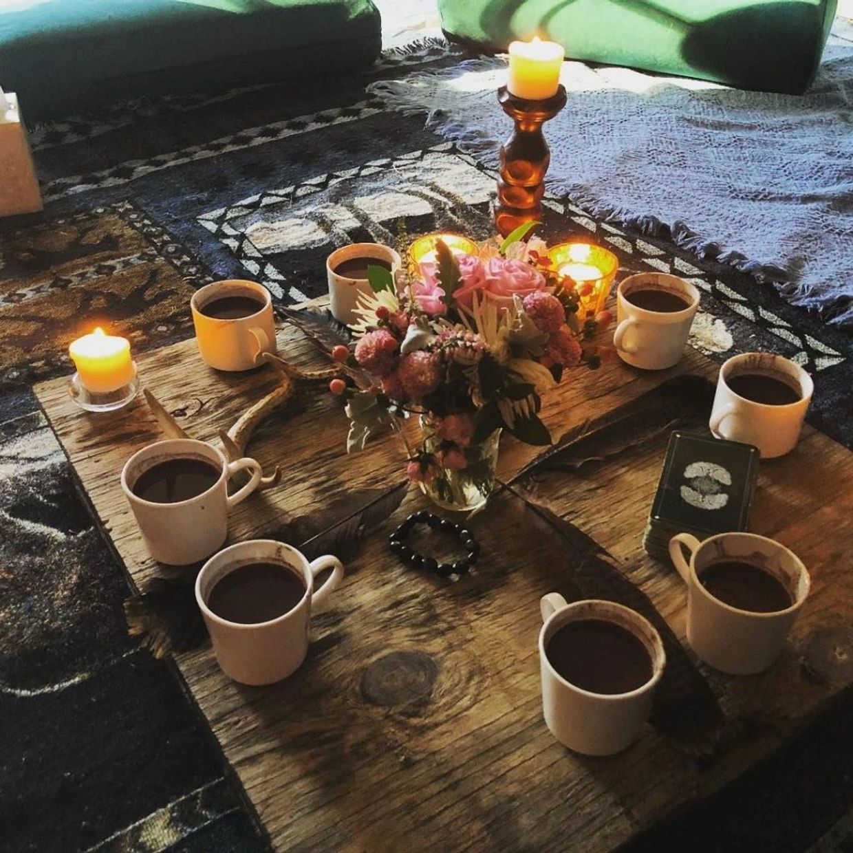 Cozy coffee setup with candles and flowers.