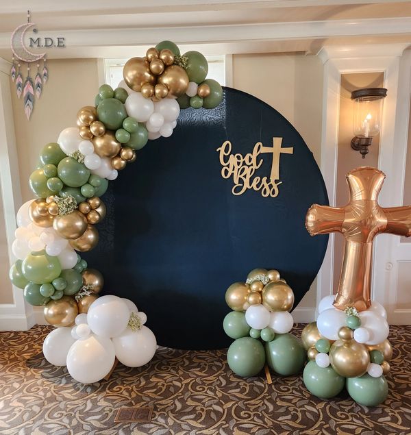 Communion party setup with balloon ring, backdrop and God bless sign. Gold cross balloon bouquet.