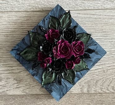 A dark, square artwork featuring deep purple and black roses surrounded by green leaves