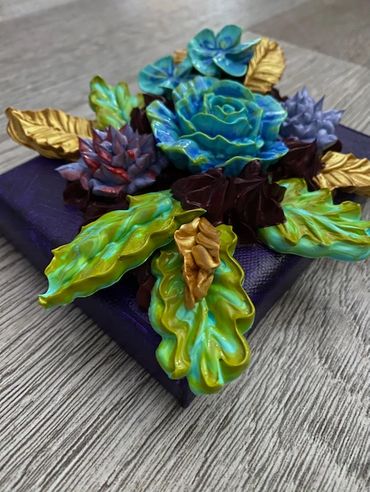 Blue and purple flowers with green and gold leaves on a dark background.