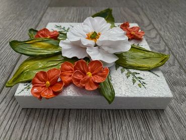 White flower with green leaves, surrounded by smaller orange blooms.