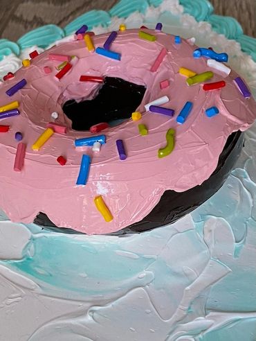 A close-up of a donut with pink icing, colorful sprinkles, and a frosted base.
