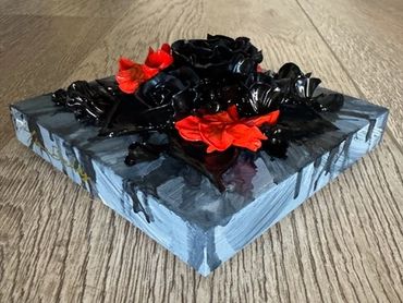 A dark square artwork featuring black roses with vibrant orange flowers on a textured background.