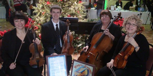 String quartet posing with instruments in festive setting.