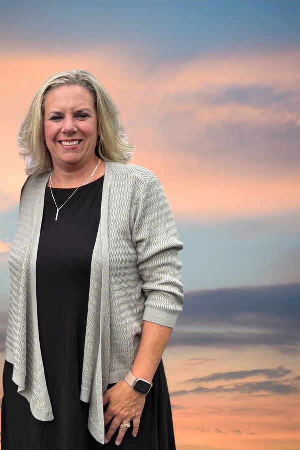 Woman smiling in front of a sunset sky.