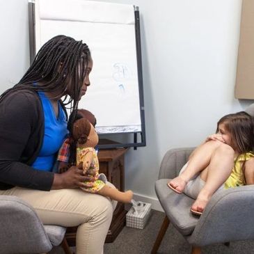 Therapist uses doll to engage shy child in a session.