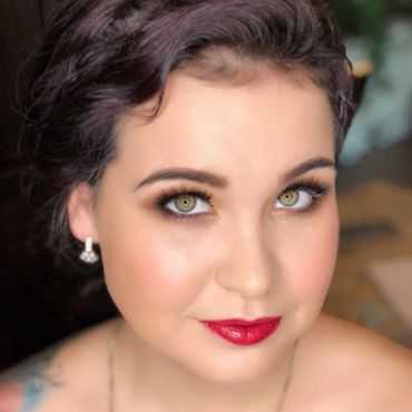 Close-up portrait of a woman with striking green eyes and red lipstick.