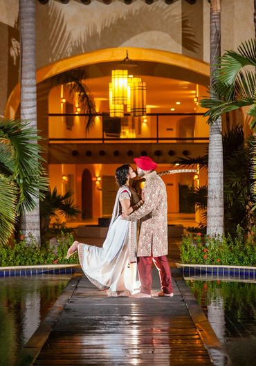 Couple in traditional attire sharing a romantic moment on a wooden pathway at night.