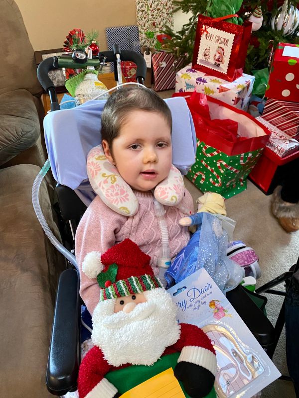 Child in wheelchair with Christmas gifts around.