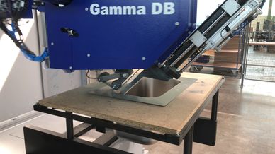 IMM Gamma CNC machine grinding a stainless-steel weld seam on a flat workpiece.