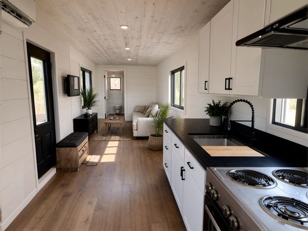 Modern tiny home interior with white cabinets and wooden floor.