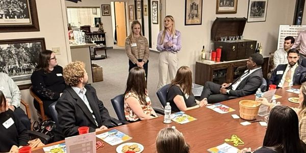 People gathered in a meeting room with two women standing and speaking.