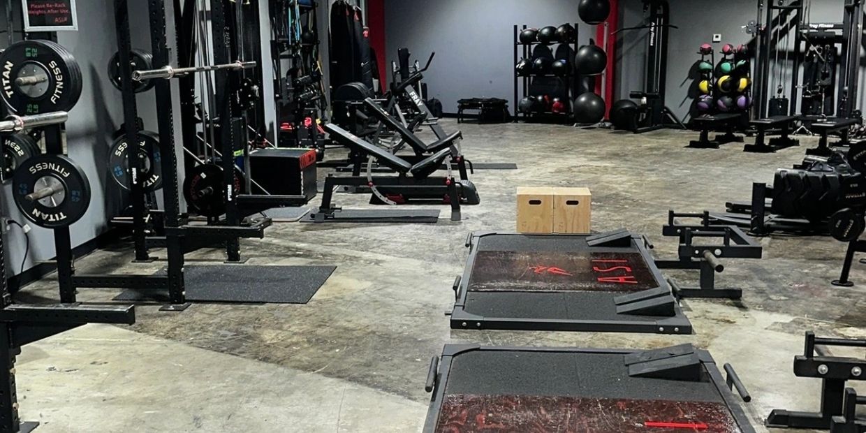 Empty gym with weightlifting equipment and benches.