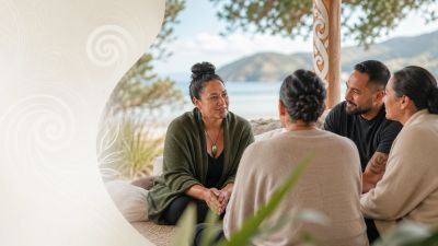 Four people engaged in a thoughtful outdoor conversation by the water.