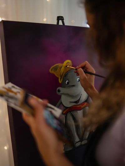 A painting of dumbo the elephant with purple background from a live artist