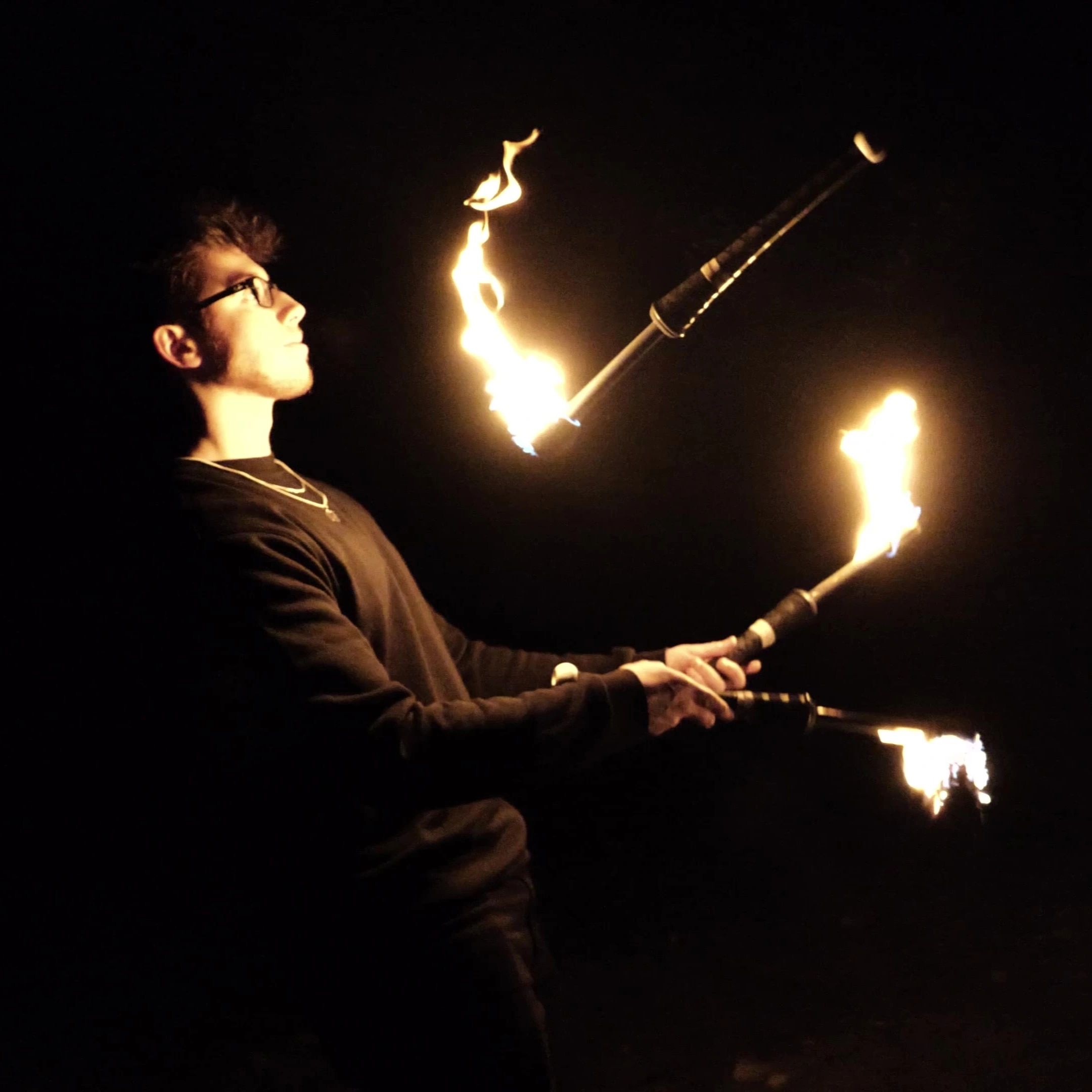 A fire juggler with 3 torches and black background