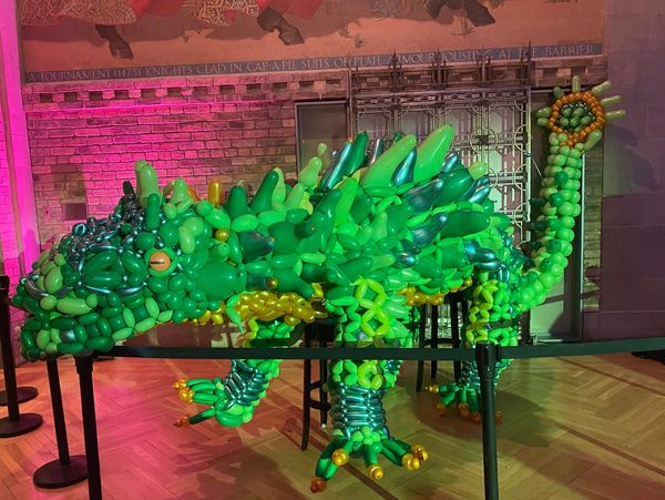 A detailed green dinosaur sculpture made entirely of balloons.
