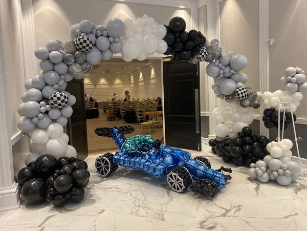 Balloon arch and race car decoration at event entrance.