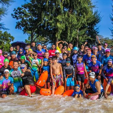 Group of triathletes posing together by the water before race.