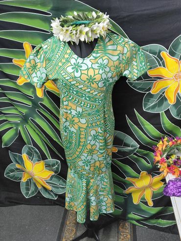 Green and yellow floral dress displayed with a white flower lei on mannequin.