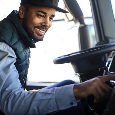 Man smiling while adjusting controls inside a vehicle cabin.