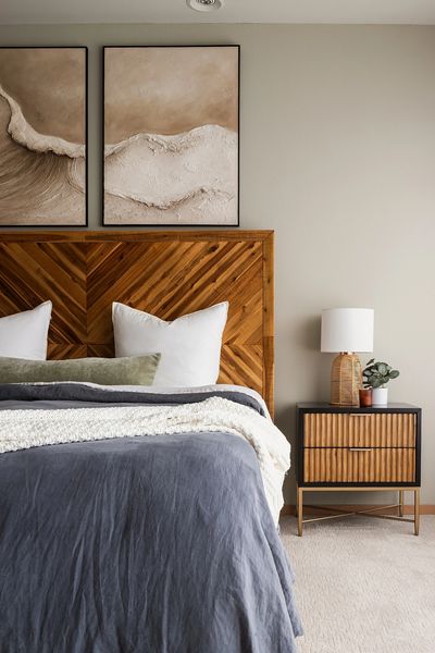 Styled bedroom with wood chevron headboard, blue linen bedding, and curated nightstand